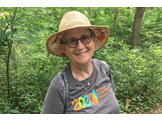 Lynn Oxenberg smiles while on a hike on a forest trail.